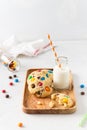 Cookies with colorful candy pieces, chopped chocolate and a bottle of milk on white background. Side view, copy space. Bakery, Royalty Free Stock Photo