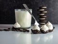 Cookies and Cream cake balls with a glass of milk, silver spoon and a pile of cookies and cookie crumbs on a white counter with a