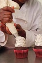 Cookies and cream cupcakes being frosted by pastry chef