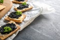 Cookies with delicious black caviar on grey table