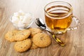 Cookies with flax seeds, sesame, sugar in bowl, spoon, transparent cup with tea on wooden table Royalty Free Stock Photo