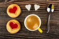 Cookies with jam hearts, cup with coffee, sugar, spoon on wooden table. Top view Royalty Free Stock Photo