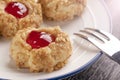 Cookies made from hazelnut shortcake with strawberry jam inside on a white plate with a patterned dessert fork Royalty Free Stock Photo