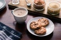 Cookies on a plate beside a cup of drinking chocolate on a wooden desk
