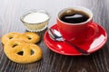 Cookies, red cup with coffee, spoon, condensed milk in bowl Royalty Free Stock Photo