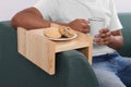 Cookies on sofa armrest wooden table. Man holding cup of drink at home, closeup Royalty Free Stock Photo