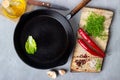 Cooking background concept - empty iron pan, cutting board and spices on a gray stone background Royalty Free Stock Photo