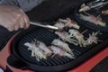 Cooking bacon wrapped enoki grilled on electric pan.