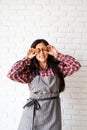 Happy woman in apron holding star shaped cookies in front of her eyes