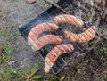 Fresh juicy shish sausages fried on coals on a barbecue grid in forest, in nature. Royalty Free Stock Photo