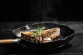 Cooking beef steak on frying grill pan on black. Food recipe background. T-bone or aged wagyu porterhouse grilled beef steak. Royalty Free Stock Photo