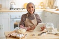 Cooking Blog. Happy Muslim Woman in Hijab Using Digital Tablet In Kitchen