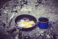 Cooking breakfast on a campfire at a summer camp. Royalty Free Stock Photo
