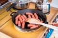 Cooking breakfast with sausages in frying skillet with wood flip