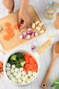 Cooking - chef`s hands preparing chicken stock broth or bouillon with vegetables in a pot. Kitchen - grey concrete worktop