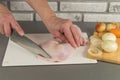 Cooking chiken. Female hand cut with a knife. Onions, carrots