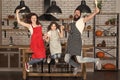 Cooking with child might be fun. Having fun in kitchen. Family mom dad and little daughter wear aprons jump in kitchen