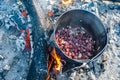 Cooking chopped smoked sausages in a cauldron on a fire