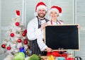 Cooking christmas meal. Man and woman chef santa hat near christmas tree hold blackboard copy space. Couple check list