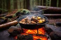 cooking cioppino over campfire with forest background