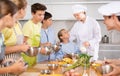 During cooking class, teenage boy stands on other side of table from male cook and looks at him Royalty Free Stock Photo