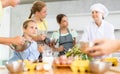 While cooking classes, small girl stands on other side of table from male cook and looks at him Royalty Free Stock Photo