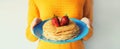 Cooking, close up woman housewife holding plate with stack of pancakes with strawberries