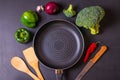 Cooking concept black background with frying pan, fresh broccoli, peppers, red onion and garlic Royalty Free Stock Photo