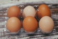 Set of six fresh brown eggs on clear plastic box. Wooden table background. Royalty Free Stock Photo