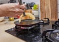 Cooking Crepe Suzette pancakes in frying pan on gas stove