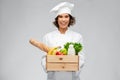 Happy smiling female chef with food in wooden box Royalty Free Stock Photo