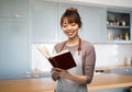 smiling woman in apron reading cook book Royalty Free Stock Photo