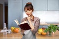 woman in apron reading cook book at kitchen Royalty Free Stock Photo