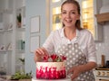 Cooking and decoration of cake with cream. Young woman pastry chef in the kitchen decorating red velvet cake Royalty Free Stock Photo