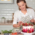 Cooking and decoration of cake with cream. Young woman pastry chef in the kitchen decorating red velvet cake