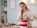 Cooking and decoration of cake with cream. Young woman pastry chef in the kitchen decorating red velvet cake Royalty Free Stock Photo