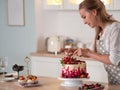 Cooking and decoration of cake with cream. Young woman pastry chef in the kitchen decorating red velvet cake Royalty Free Stock Photo