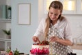 Cooking and decoration of cake with cream. Young woman pastry chef in the kitchen decorating red velvet cake Royalty Free Stock Photo