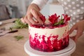 Cooking and decoration of cake with cream. Young woman pastry chef in the kitchen decorating red velvet cake Royalty Free Stock Photo