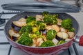 Cooking delicious vegetable vegetarian stew in a frying pan on a gas stove. The recipe includes eggplant, broccoli and