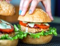 Cooking delicious homemade burgers with cutlet, salad, tomato and sesame burger bun, close-up. Delicious homemade food, fast food Royalty Free Stock Photo