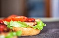 Cooking delicious homemade burgers with cutlet, salad, tomato and sesame burger bun, close-up. Delicious homemade food, fast food Royalty Free Stock Photo