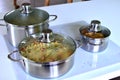 Cooking dinner on the electric stove in the modern kitchen. Chrome food pans