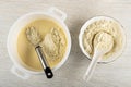 Cooking dough for pancakes. Whisk in pan with dough, bowl with flour on table. Top view Royalty Free Stock Photo