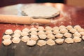 Cooking dumplings. Rows of raw dumplings and rolled dough in the background