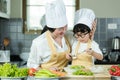 Cooking Family. Chef kid boy and mother making and leaning fresh vegetables salad