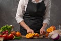 Cooking festive chicken for baking, the chef cuts an orange against a background of vegetables and fruits. Recipe book and