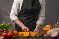 Cooking festive chicken for baking, the chef cuts an orange against a background of vegetables and fruits. Recipe book and