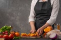 Cooking festive chicken for baking, the chef cuts an orange against a background of vegetables and fruits. Recipe book and