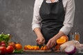 Cooking festive chicken for baking, the chef cuts an orange against a background of vegetables and fruits. Recipe book and